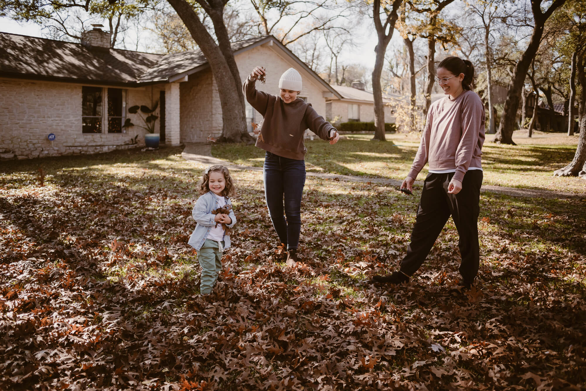 Candid moment of a family laughing in the leaves outside their home in Austin