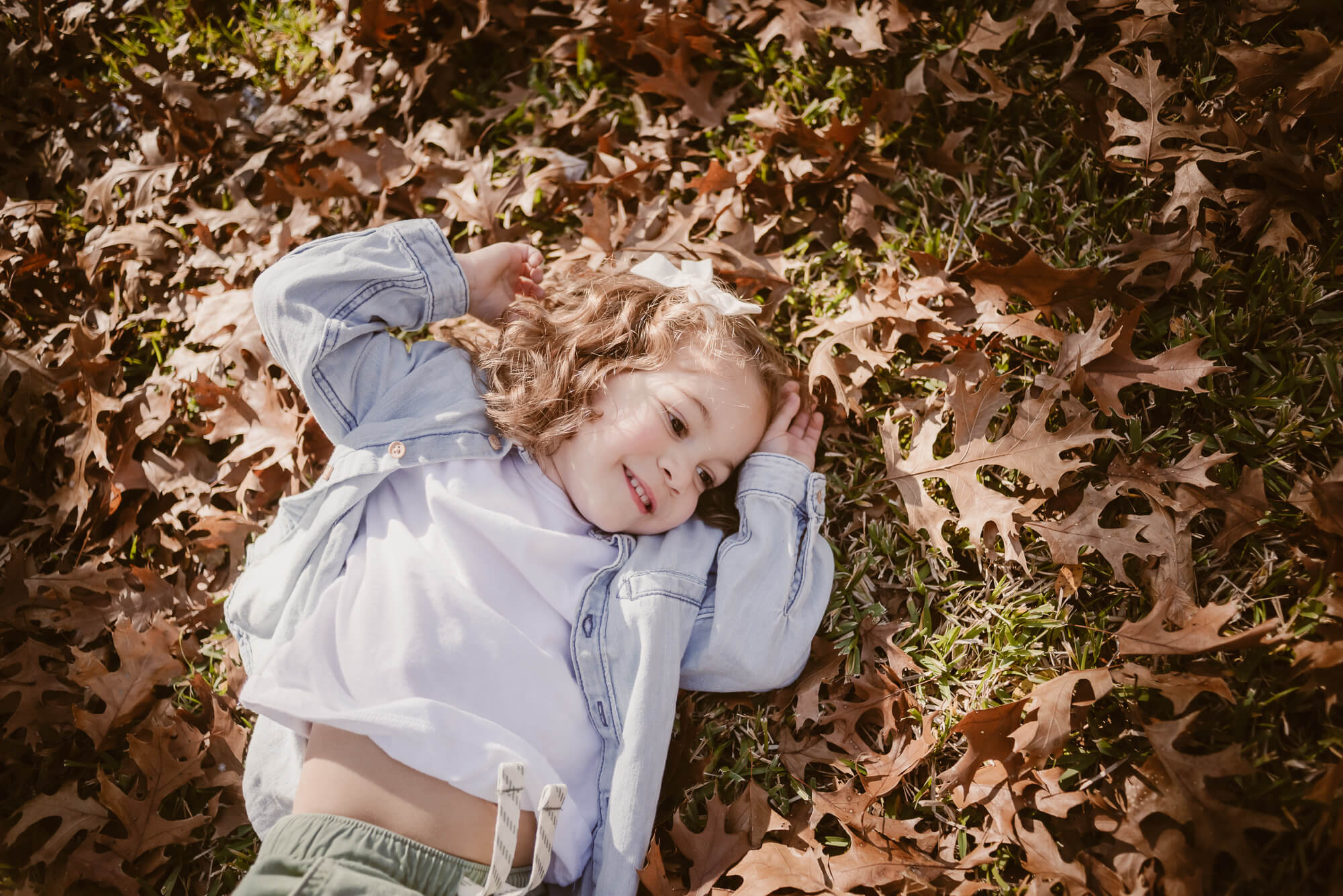 toddler playing outside in the front yard in leaves during an at home family photoshoot in austin texas