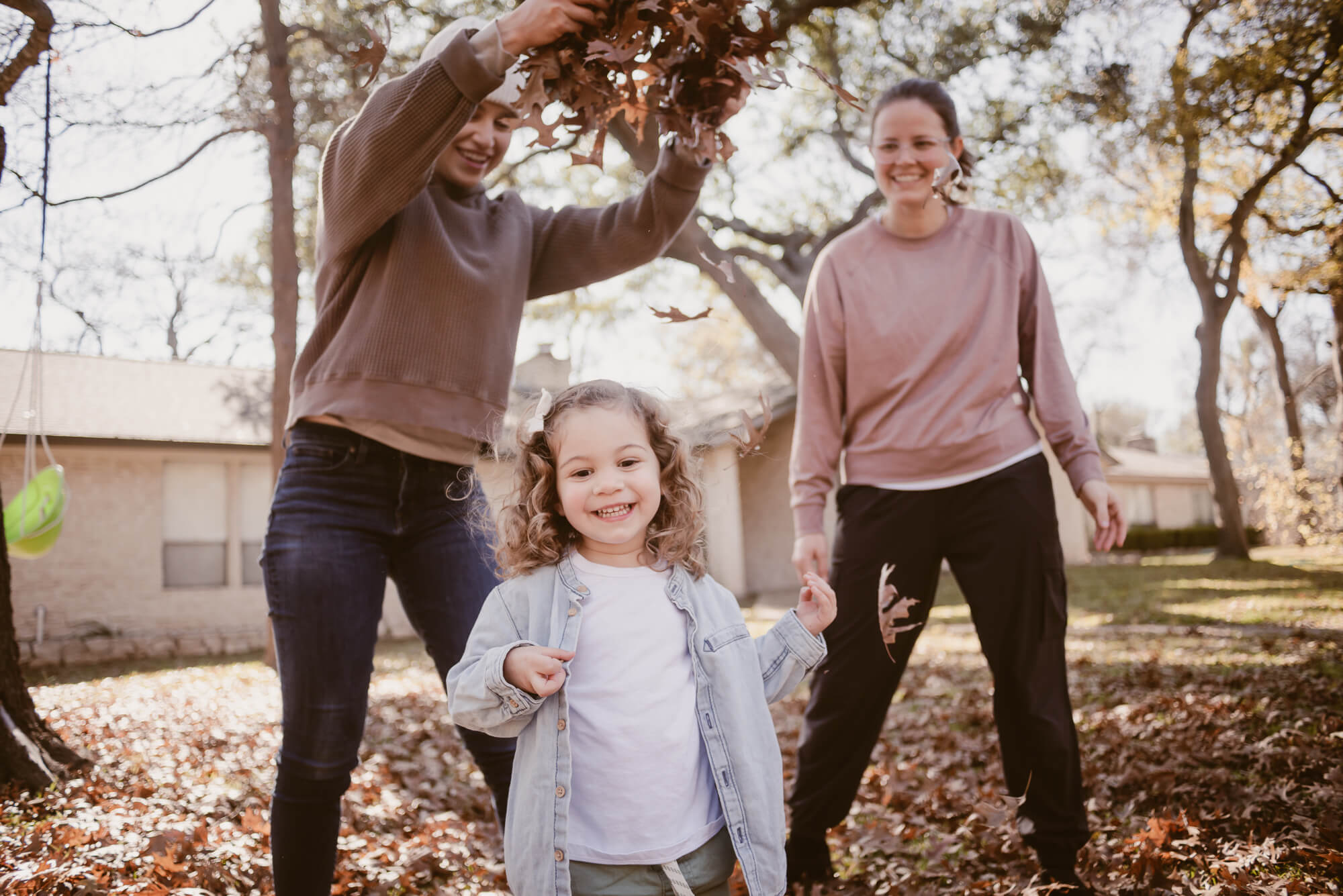 Family playing in leaves together in their front yard during an at-home family photoshoot