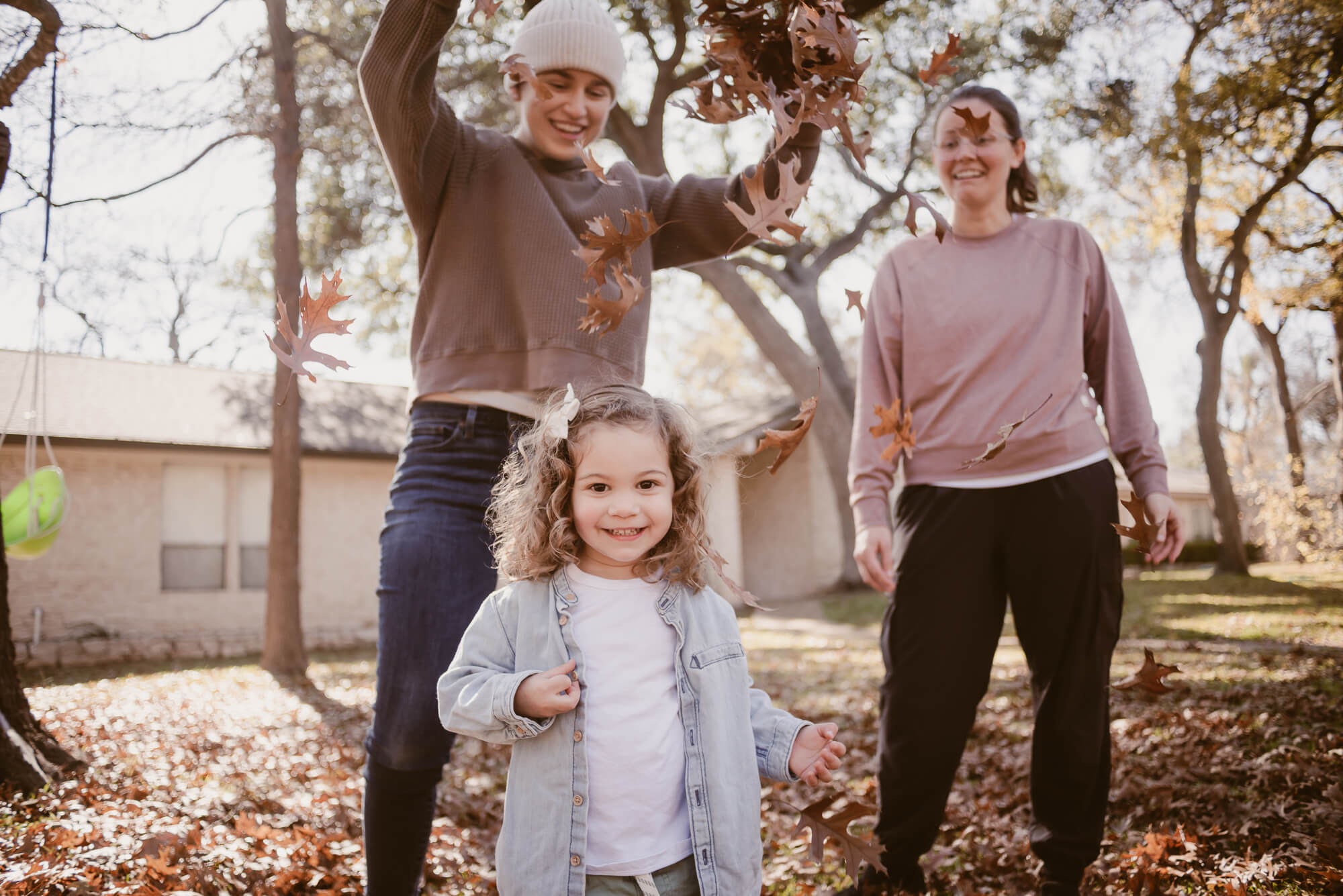 parents dropping leaves on their toddler during an at home family photoshoot in austin texas