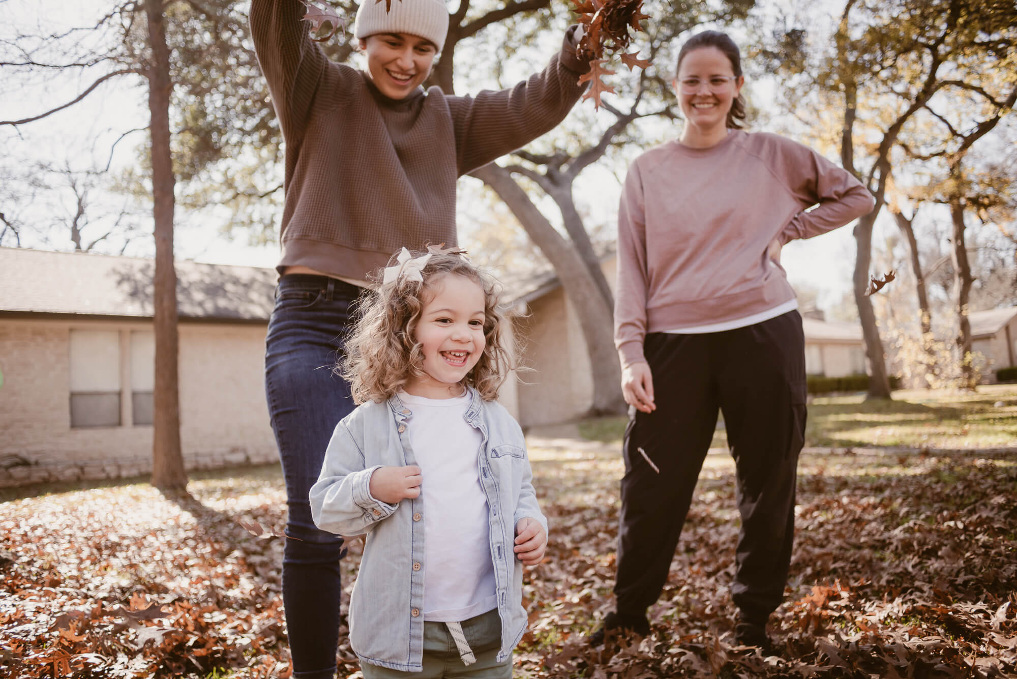 Family playing in leaves together in their front yard during an at-home family photoshoot