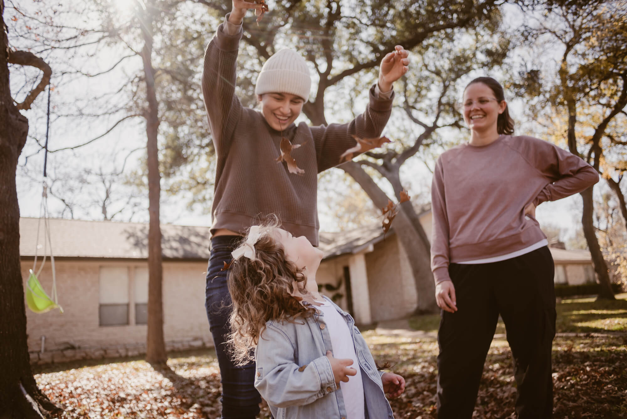 parents dropping leaves on their toddler during an at home family photoshoot in austin texas