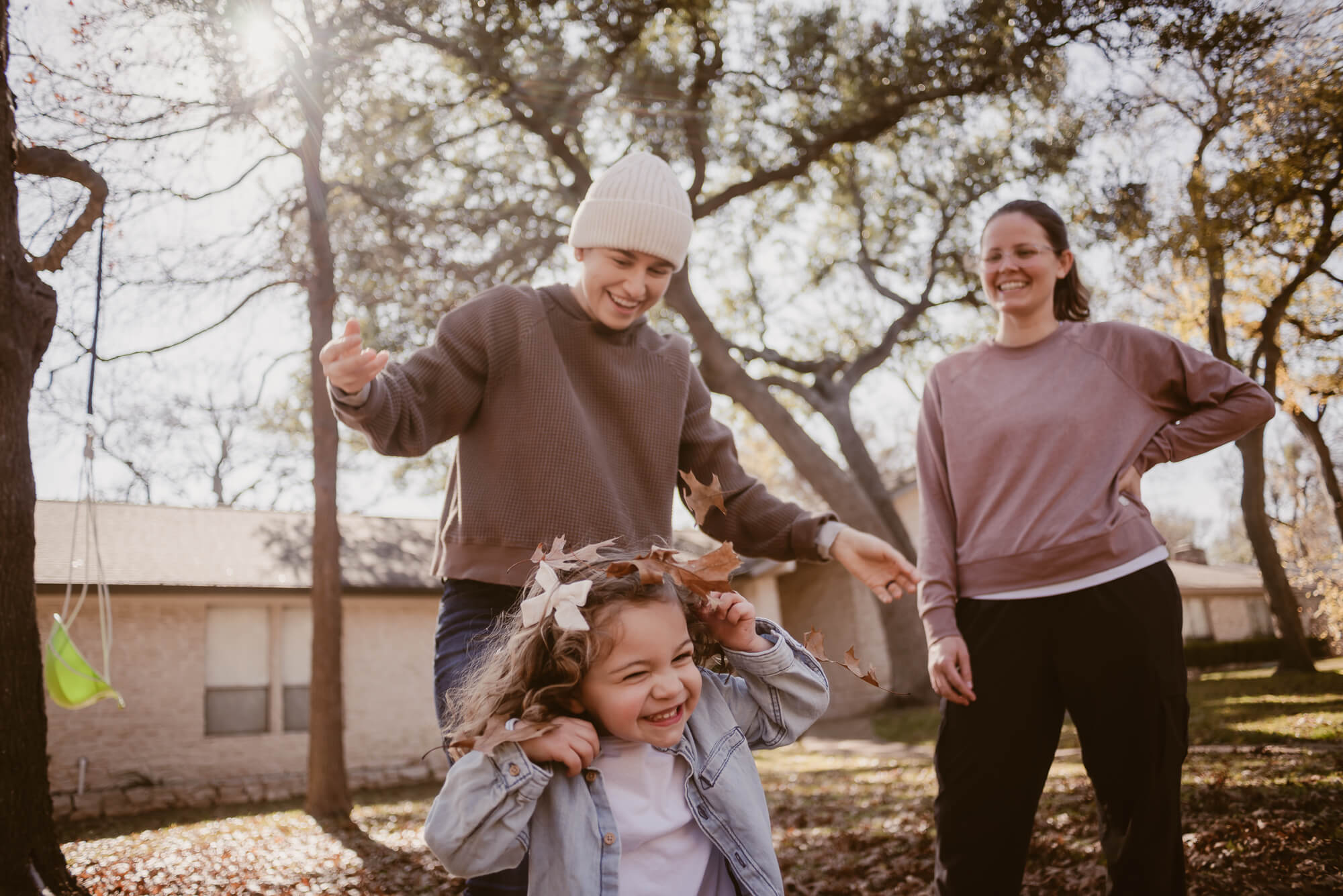 parents dropping leaves on their toddler during an at home family photoshoot in austin texas