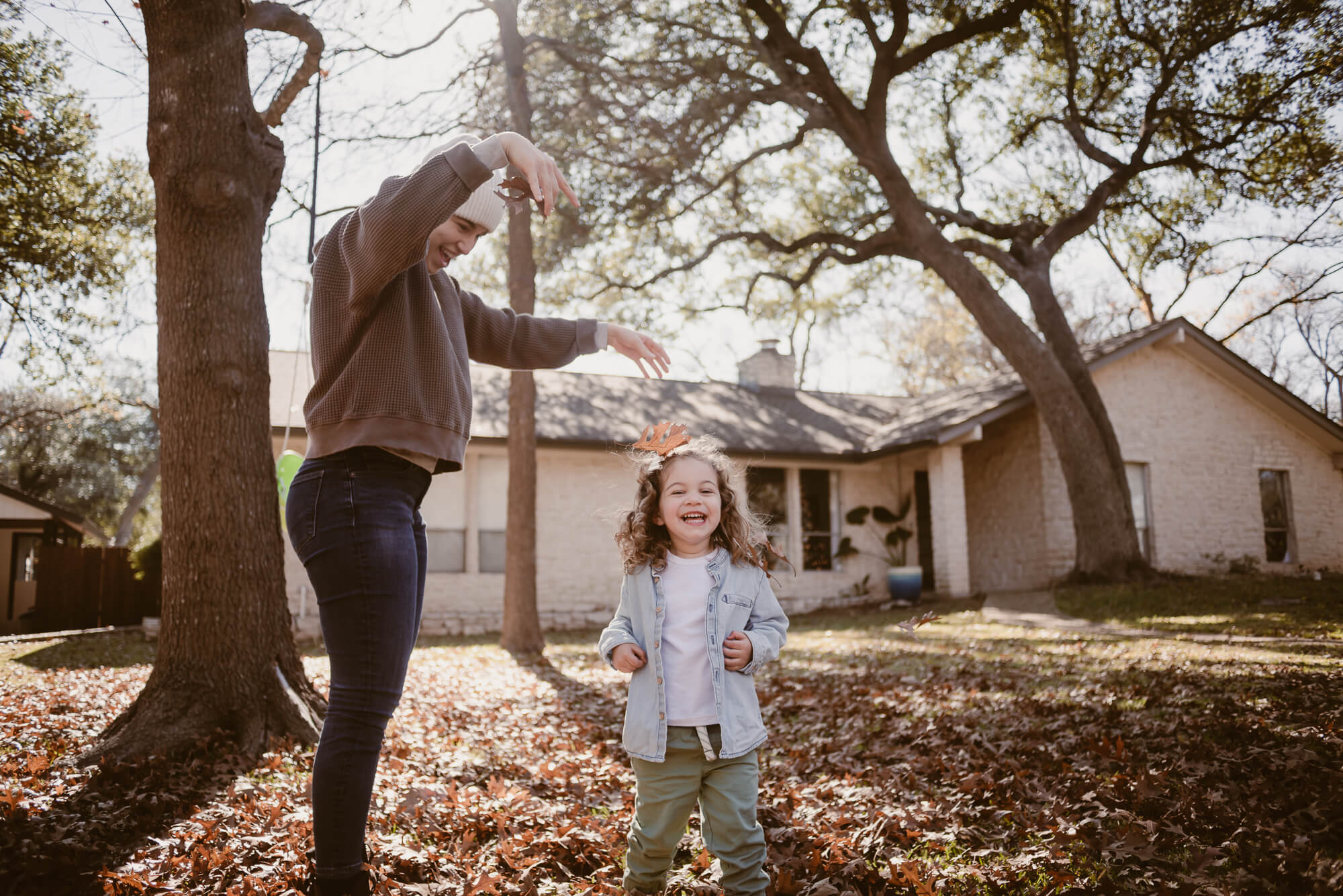 parents dropping leaves on their toddler during an at home family photoshoot in austin texas