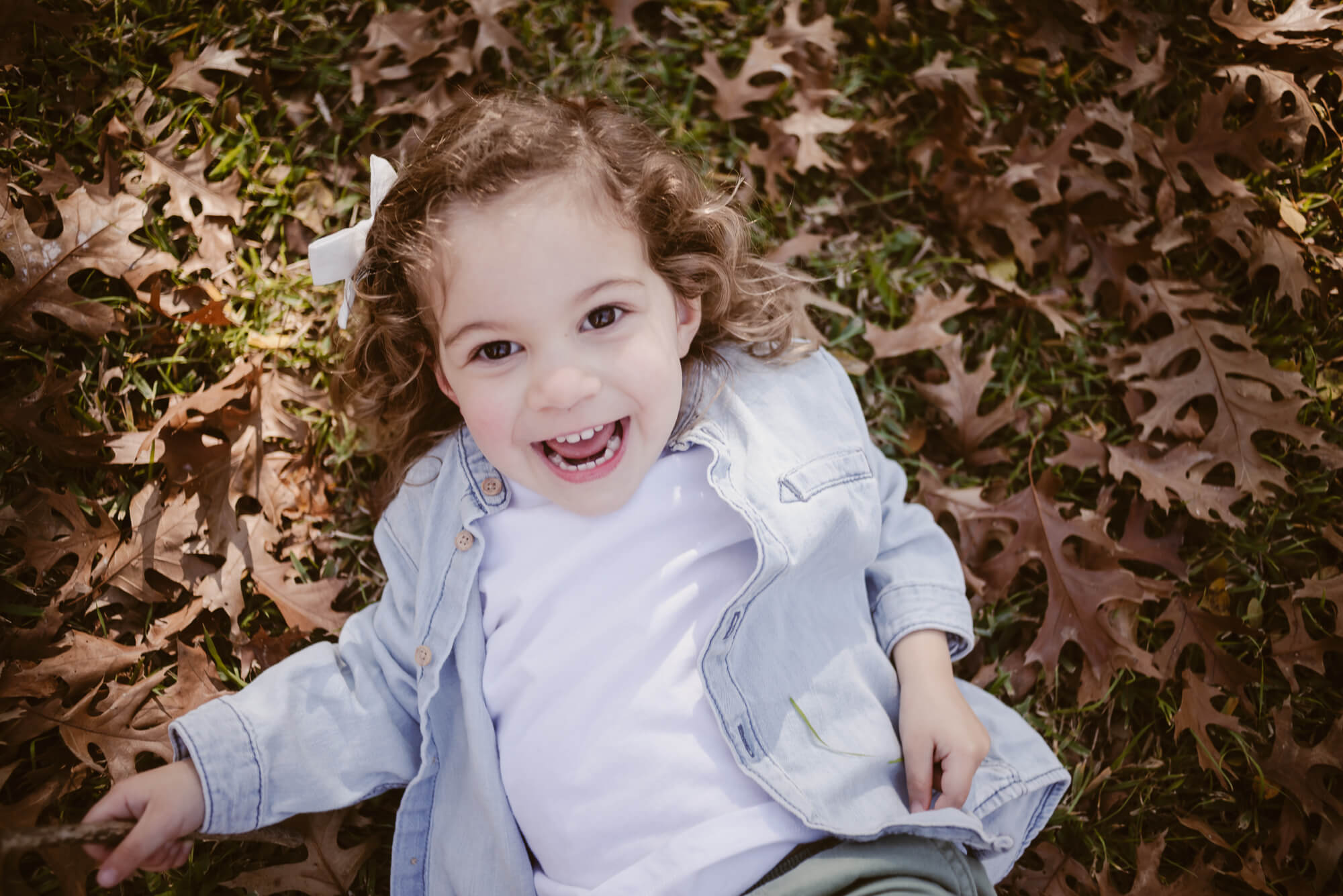 Toddler playing in a pile of leaves in the front yard during an at-home family photoshoot in Austin